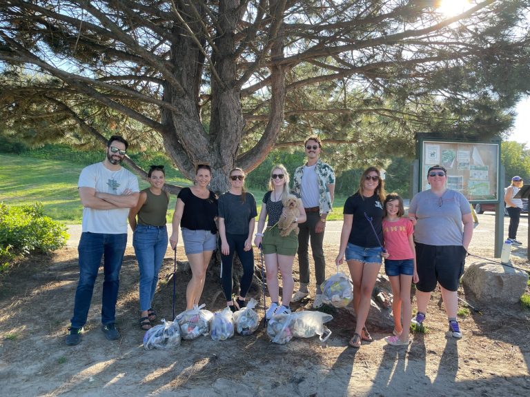 Group of ten people with bags of trash at a park clean-up event.